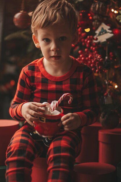 Retrato de una niña linda jugando con el árbol de Navidad en casa
