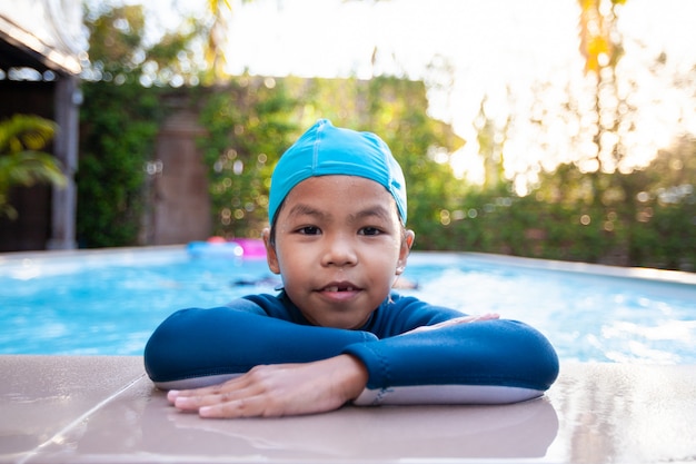 Retrato de niña linda niña asiática vistiendo traje de baño en la piscina