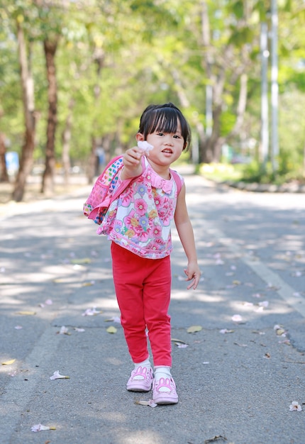 Retrato de la niña linda en el parque público con la flor de la explotación agrícola para usted.