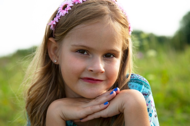 Retrato de una niña linda en un prado. Hermosa niña de 7-9 años con cabello castaño rizado.