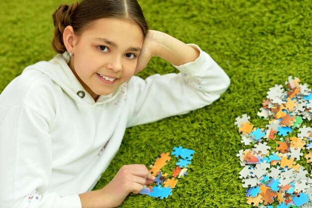 Retrato de niña linda recogiendo piezas de un rompecabezas