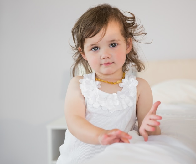 Retrato de niña linda sentada en la cama