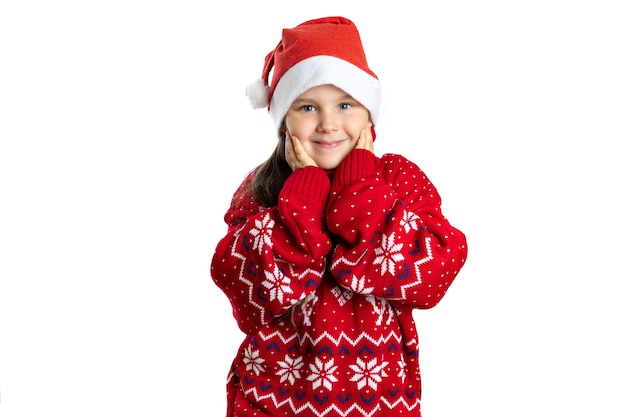 Retrato de niña linda sonriente en suéter rojo de navidad con renos tocando la cara con las palmas aisla ...