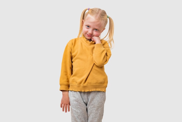 Retrato de una niña linda con una sudadera amarilla aislada sobre un fondo gris