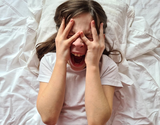 Retrato de niña llorando y gritando de horror en la cama