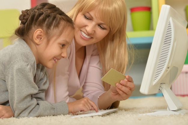 Retrato de una niña con madre haciendo compras en línea en casa