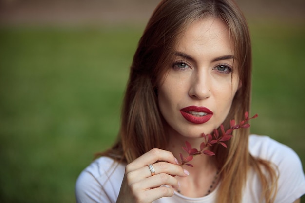 Retrato de una niña con maquillaje brillante y labios Marsala con una planta roja