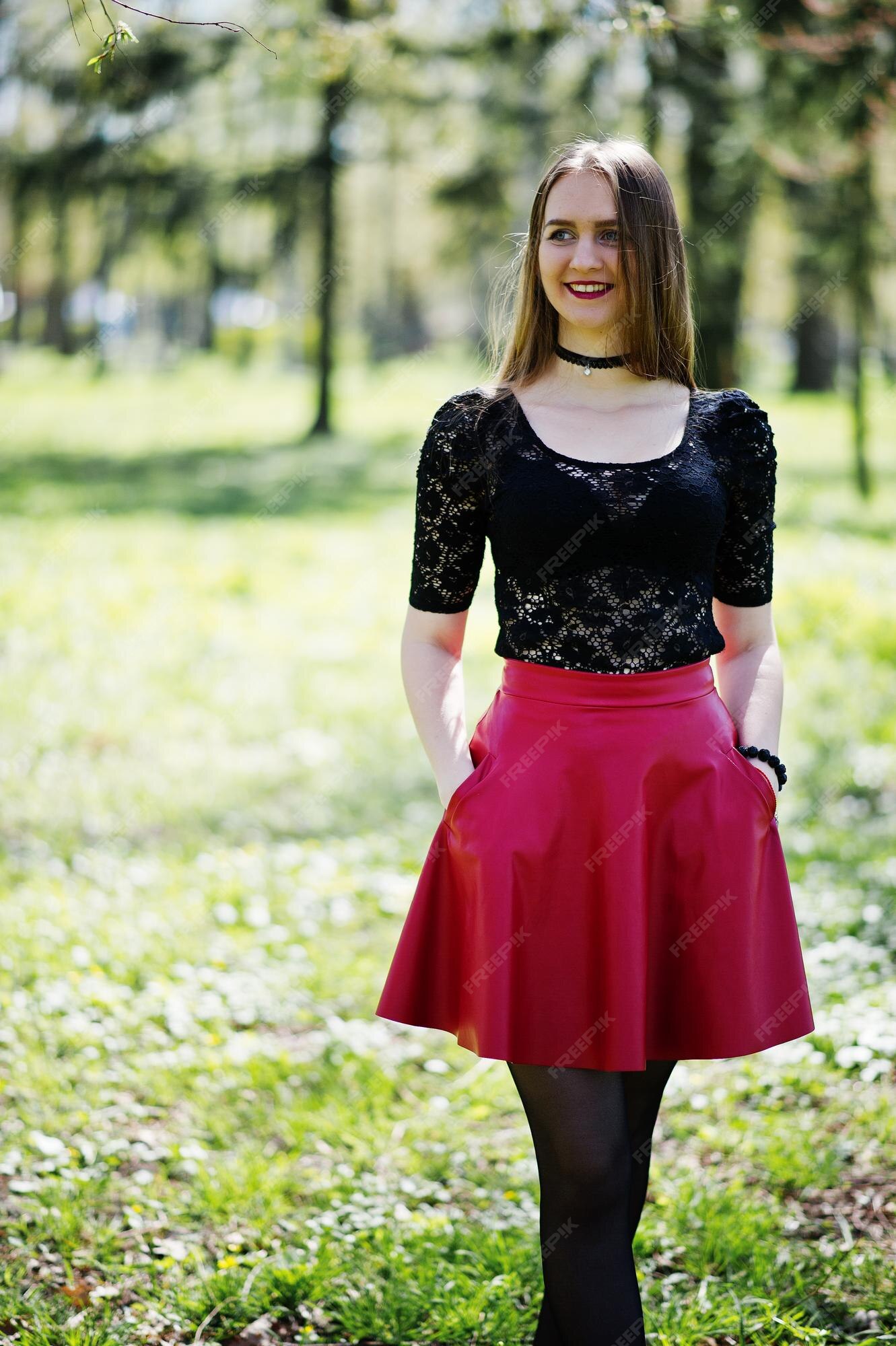 Retrato de niña con maquillaje brillante con labios rojos collar de gargantilla negra en el cuello y falda de cuero rojo en park | Foto Premium