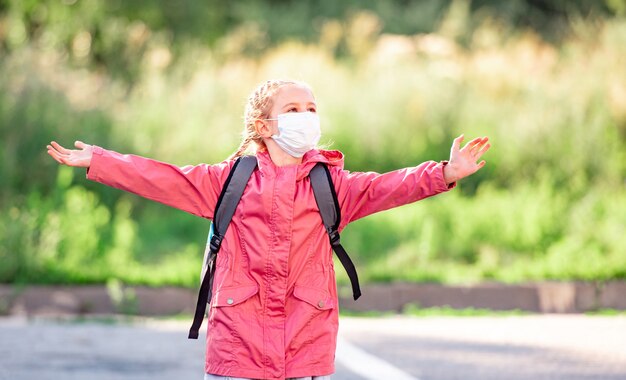 Retrato de niña con máscara corriendo al aire libre después de la escuela