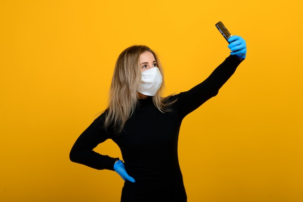 Retrato de una niña con una máscara médica, que se pone un guante de goma.