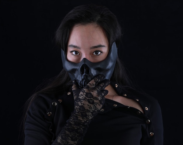 Retrato de una niña con una máscara de monstruo sobre un fondo negro