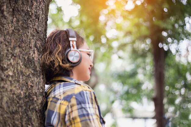 Foto retrato de una niña mirando hacia otro lado contra el tronco de un árbol