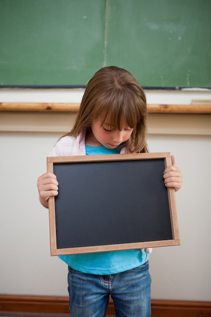 Retrato de una niña mirando una pizarra de la escuela