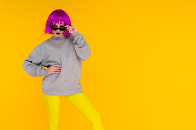 Retrato de niña de moda en amarillo. Mujer joven de estilo loco en peluca rosa