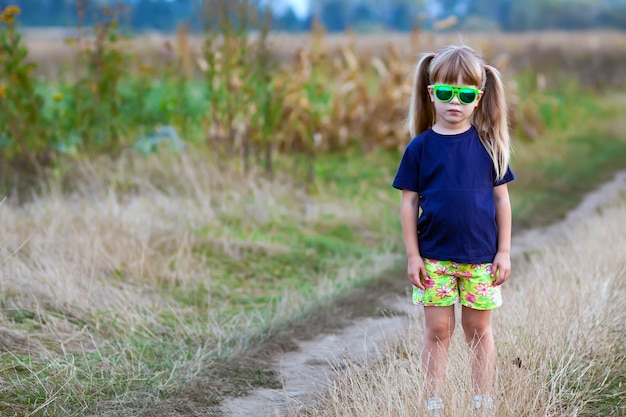 Retrato de niña de moda en gafas de sol verdes al aire libre