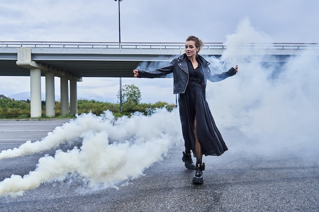Retrato de niña modelo en ropa negra con el efecto del humo, niebla blanca