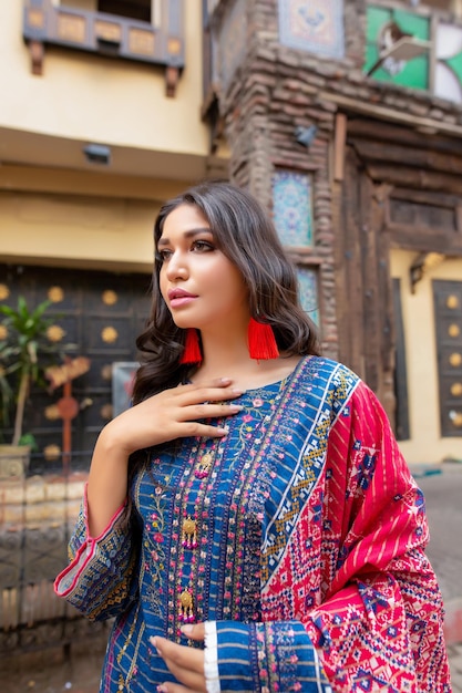 Retrato de niña modelo sosteniendo su vestido Desi para sesión de moda en la calle de la ciudad amurallada de Lahore