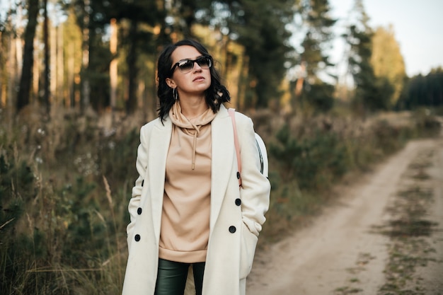 Retrato de niña morena con gafas de sol en el sendero del bosque