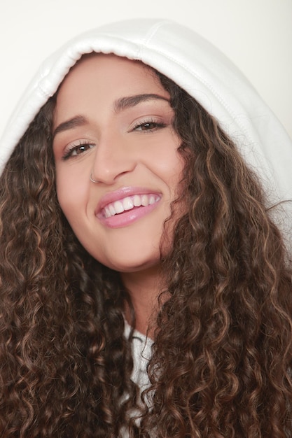 Retrato de niña morena de pelo largo y rizado sonriendo a la cámara