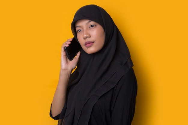 Retrato de niña musulmana con un teléfono inteligente sobre fondo amarillo