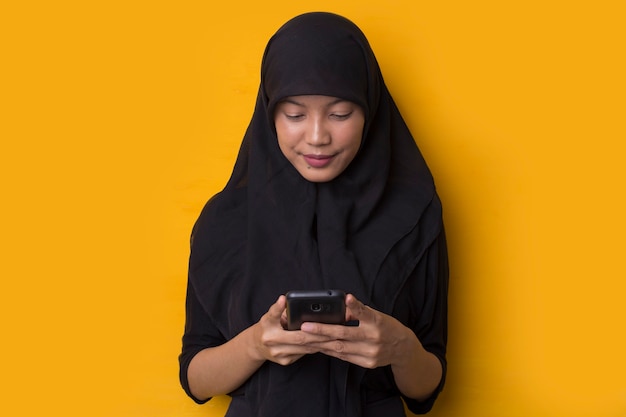 Retrato de niña musulmana con un teléfono inteligente sobre fondo amarillo