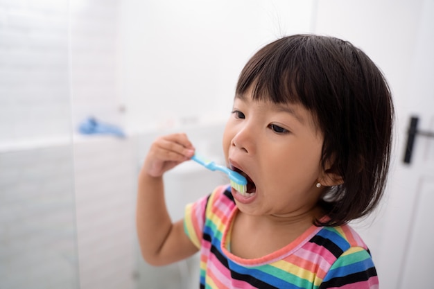 Retrato de una niña muy inteligente que se cepilla los dientes es una actividad de rutina