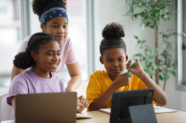 Foto retrato de una niña negra brillante con aparatos ortopédicos escribe en el cuaderno de ejercicios smiles junior classroom con un grupo diverso de niños aprendiendo cosas nuevas