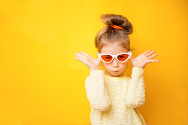 Retrato de niña niño con gafas sobre un fondo amarillo. Copia espacio