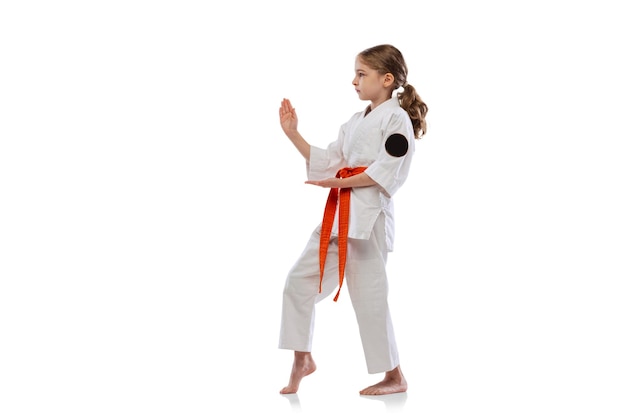 Retrato de niña, niño en kimono formación karate aislado en blanco. Arte marcial