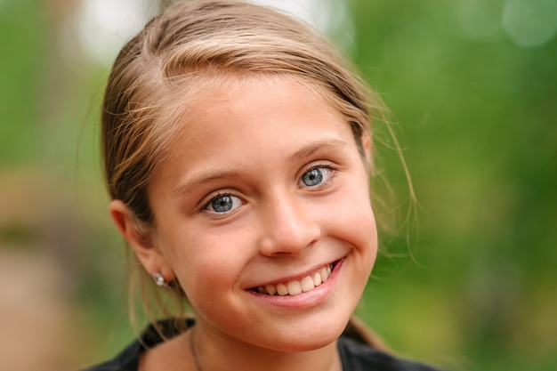 Retrato de una niña con ojos azules un fondo verde natural