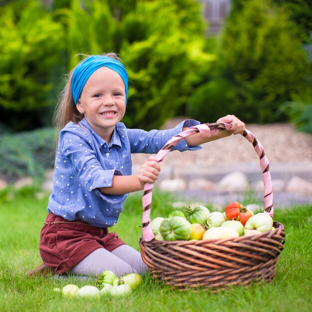 Retrato de niña con otoño cosecha de tomate en cestas