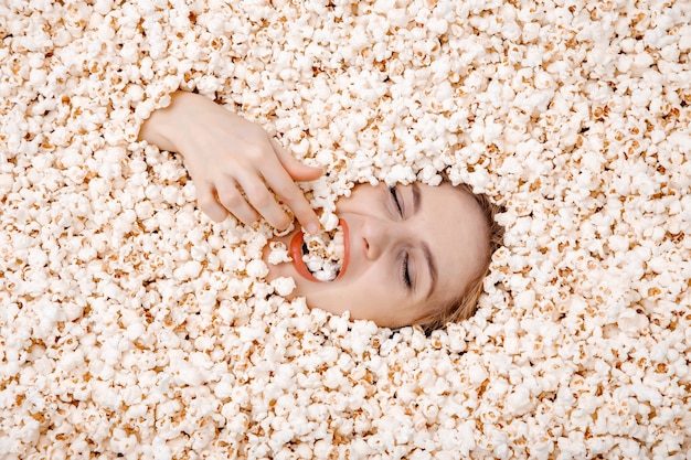 Retrato de niña en palomitas de maíz. Mujer joven enterrada en palomitas de maíz.