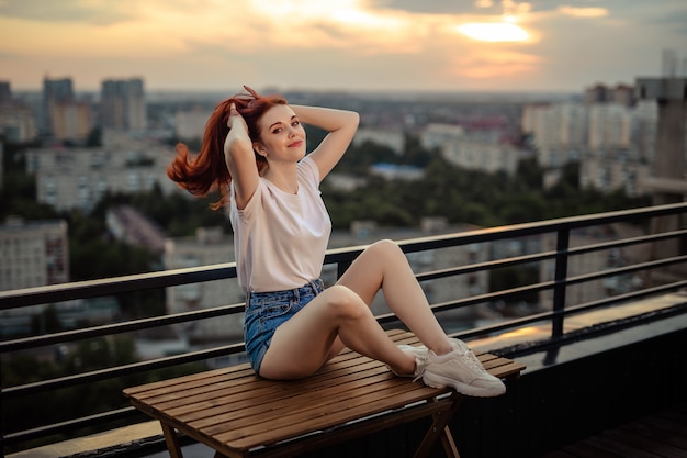 Retrato de una niña pelirroja en el techo al atardecer