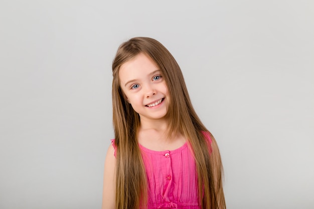 Retrato de una niña con el pelo largo en ropa de color rosa. niña feliz sonriendo en el espacio en blanco aislado