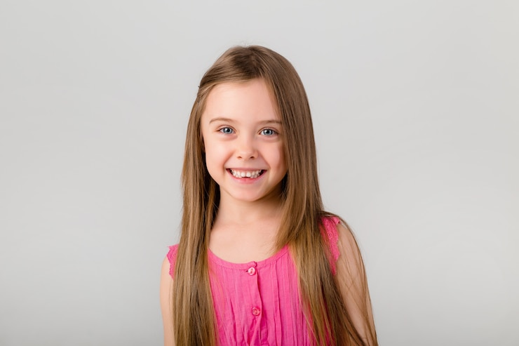 Foto retrato de una niña con el pelo largo en ropa de color rosa. niña feliz sonriendo en el espacio en blanco aislado