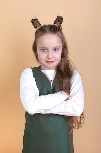 Retrato de una niña con el pelo largo en un vestido de verano y una chaqueta sobre un fondo beigePosando un peinado moderno Sonriendo Atelier