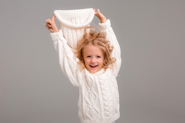 Retrato de una niña de pelo rizado en un gorro de invierno blanco de punto