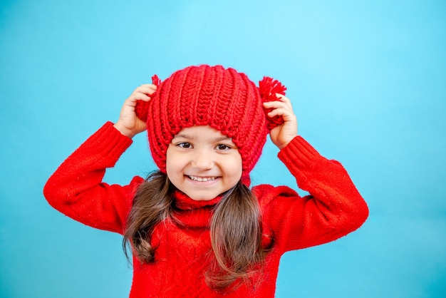 Retrato de una niña de pelo rizado en un sombrero rojo tejido en invierno niña con cabello oscuro