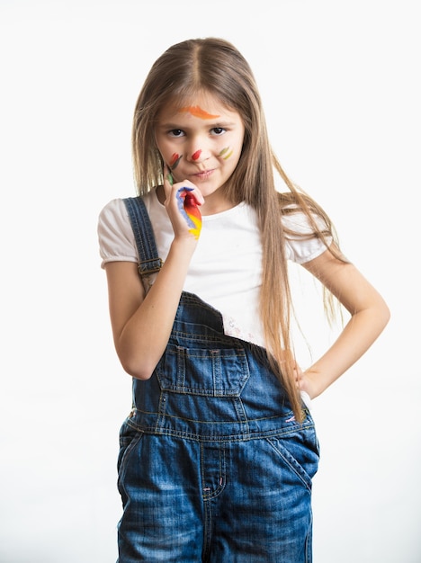 Retrato de niña pensativa con la cara pintada contra el fondo blanco.