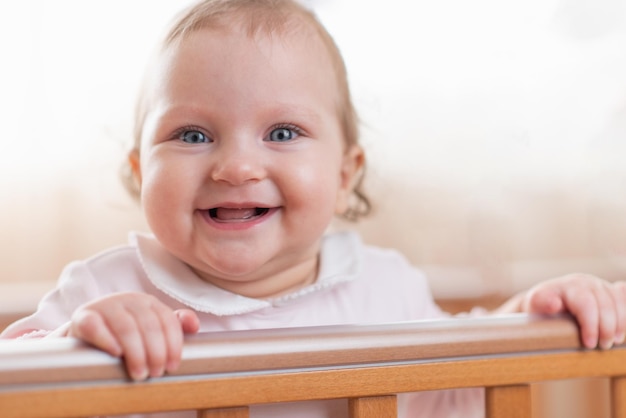 Retrato de una niña pequeña feliz y riendo en una cuna