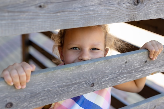 Retrato de niña pequeña mirando a la cámara Niño asomando a través de la valla