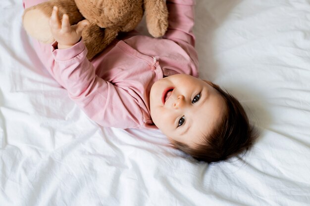 Retrato de una niña pequeña sonriendo mientras está acostado en la cama