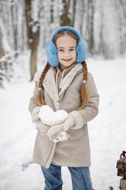 Retrato de una niña de pie en el bosque de invierno y posando para una foto