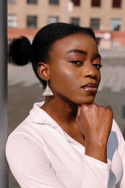 Retrato de una niña de piel oscura con maquillaje brillante cerca del edificio