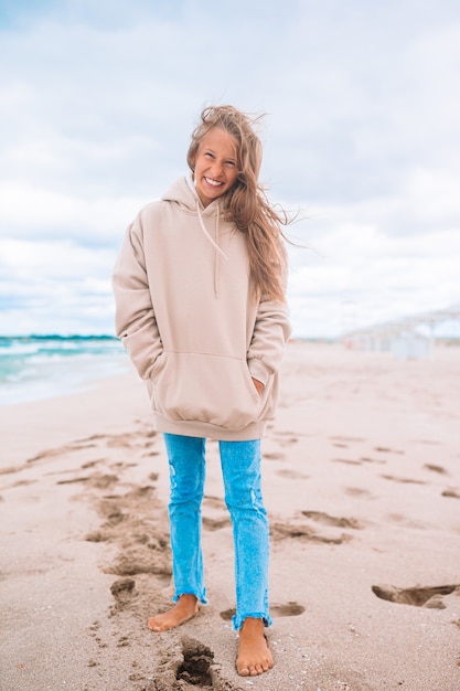 Retrato de niña en la playa en clima ventoso y nublado