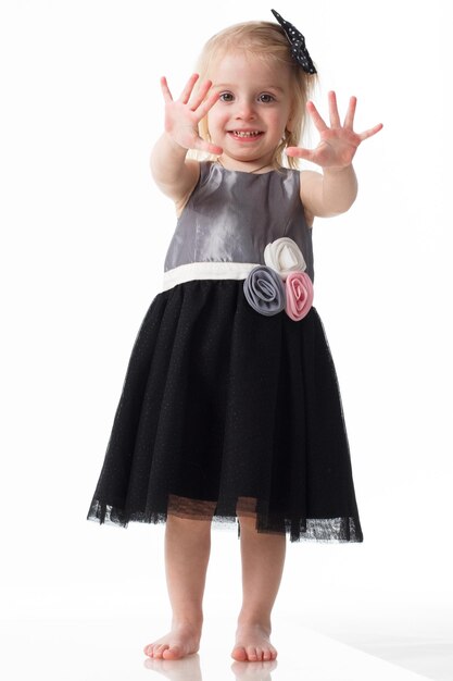 Retrato de una niña positiva y elegante con un vestido de verano se regocija con el viento que sopla y mueve su vestido y cabello El concepto de belleza y moda Aislado en el fondo blanco