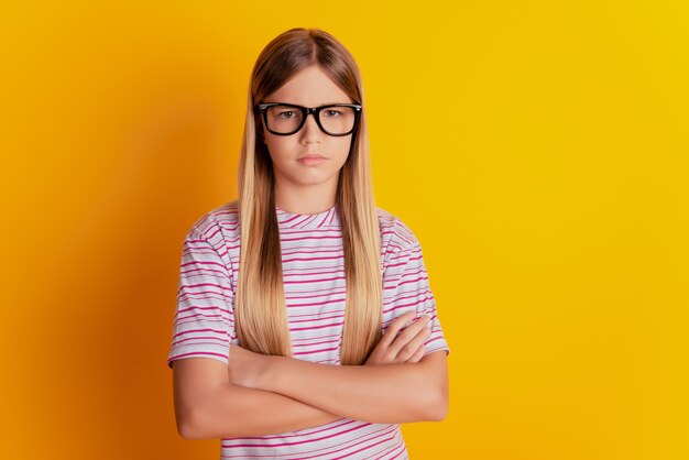 Retrato de niña preadolescente ofendida con los brazos cruzados aislado sobre fondo amarillo