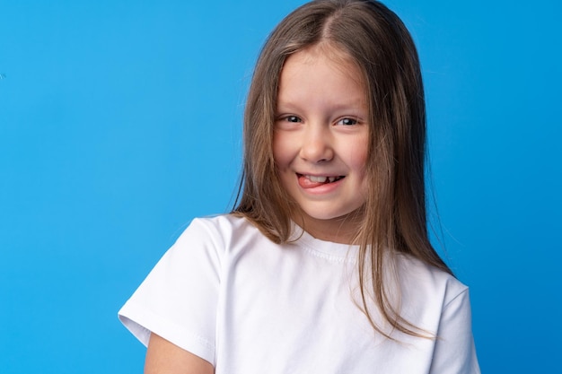 Retrato de una niña preadolescente sonriente sobre fondo azul.