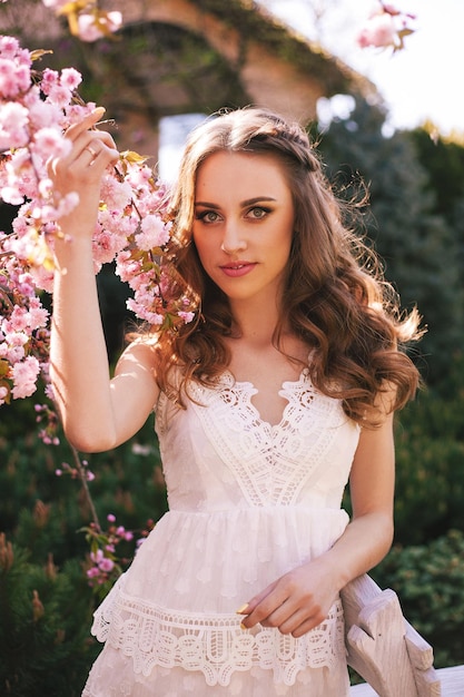 Retrato de una niña en primavera con un hermoso peinado y maquillaje profesional en el jardín cerca de las magnolias