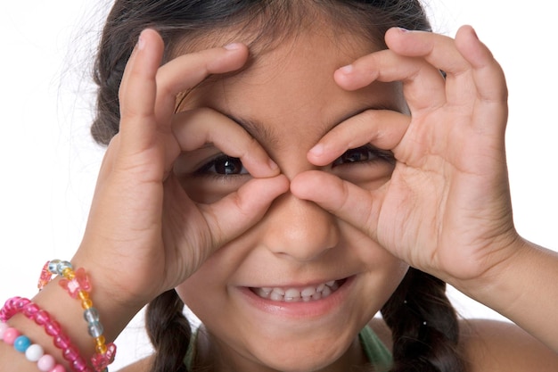 Foto retrato de una niña que hace gafas con los dedos de cerca